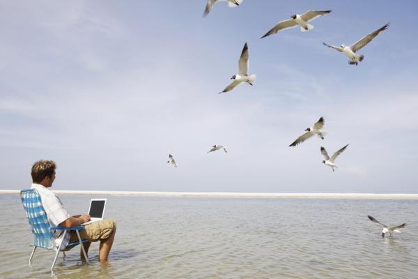 Hombre en la playa con portátil