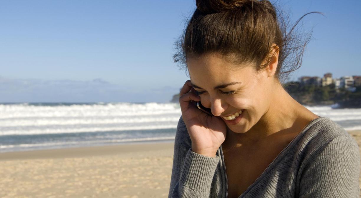 Fotografía chica en la playa hablando por móvil