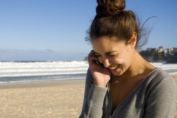 Fotografía chica en la playa hablando por móvil