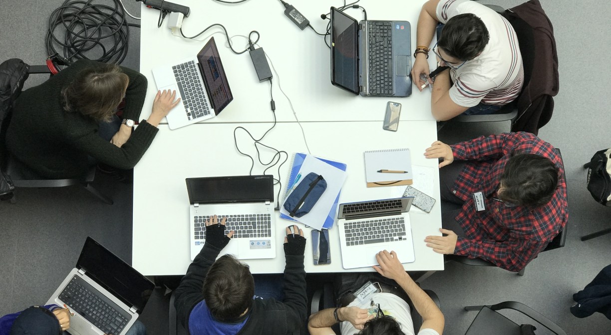 Imagen de varios jóvenes con ordenadores alrededor de una mesa