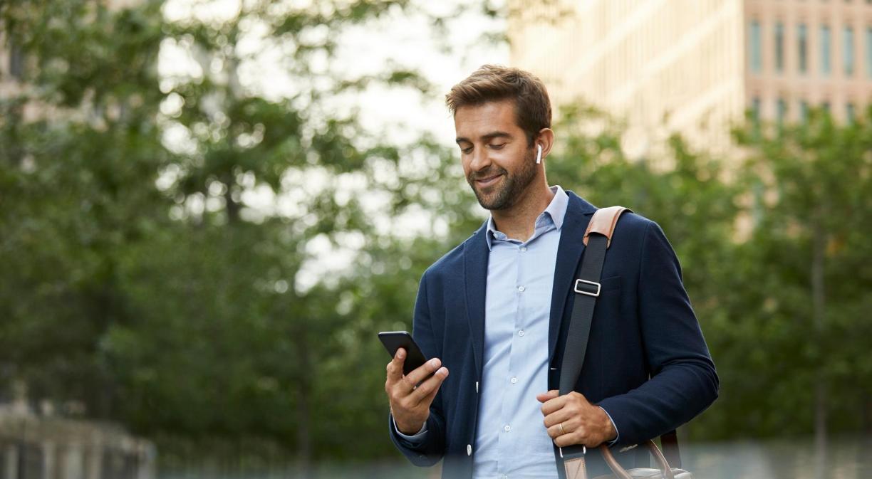 Hombre de negocios confiado sonriente que usa smartphone