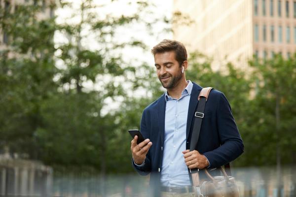 Hombre de negocios confiado sonriente que usa smartphone