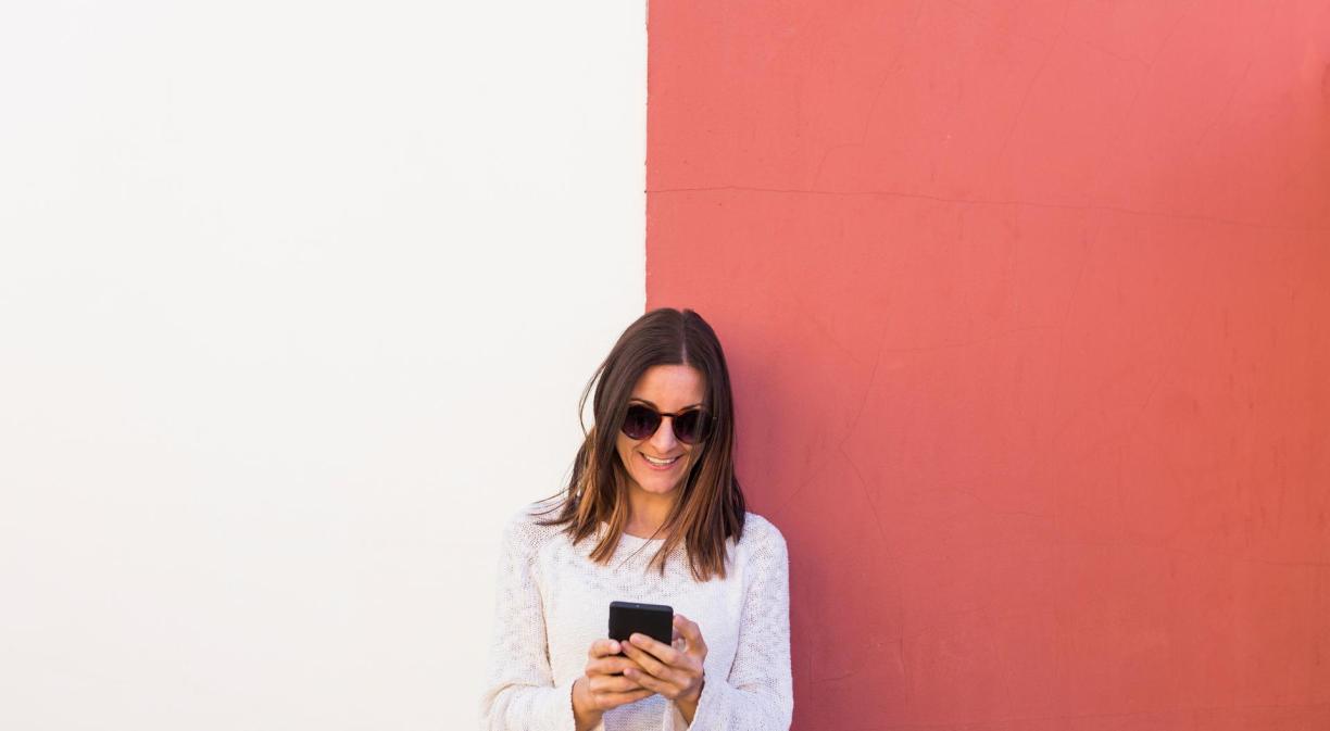 Mujer usando móvil delante de una pared