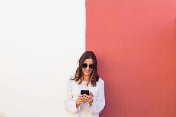 Mujer usando móvil delante de una pared