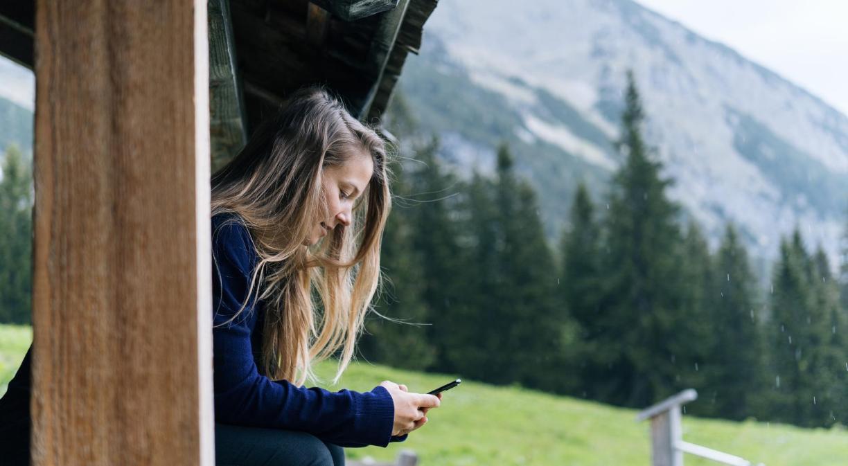 Chica en las montañas usando móvil