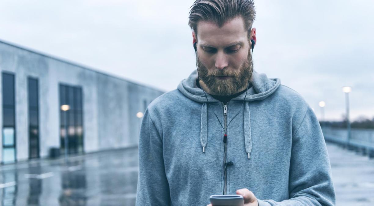 Hombre con barba usando en la calle un móvil