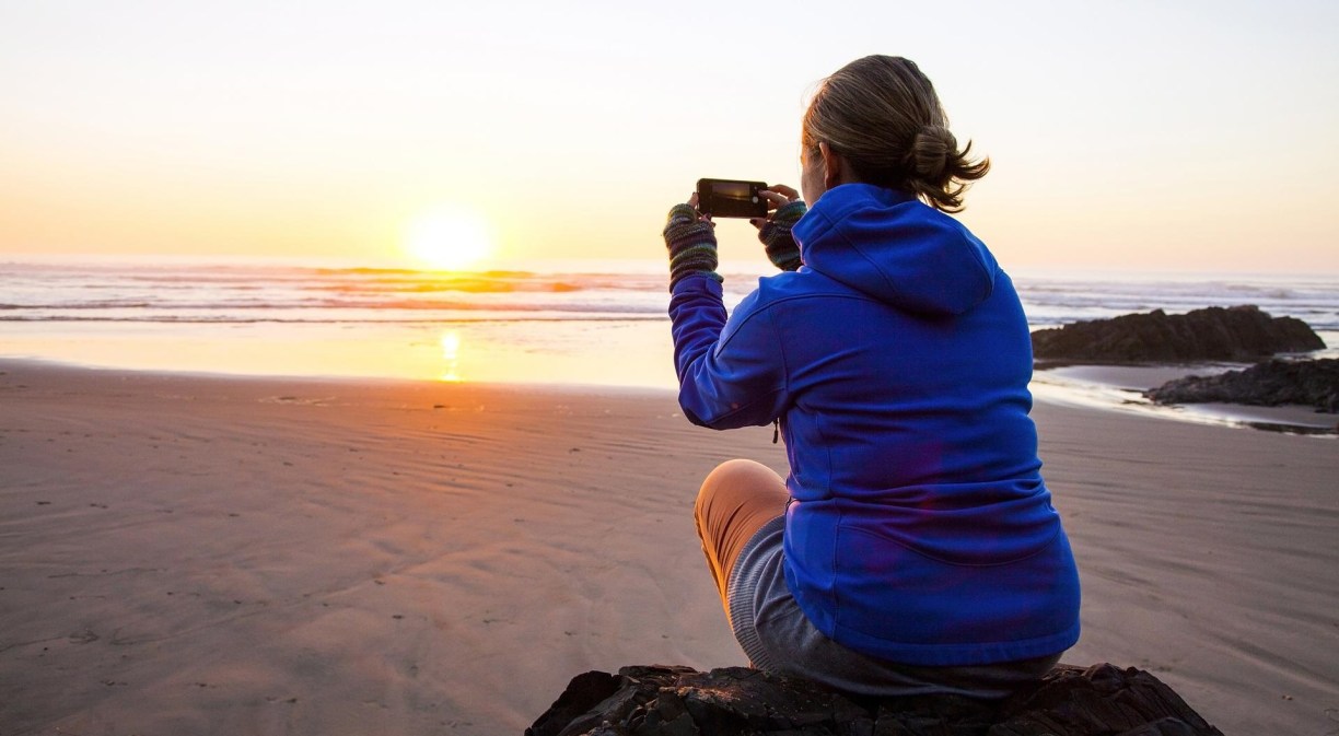Imagen mujer sacando foto puesta de sol con móvil