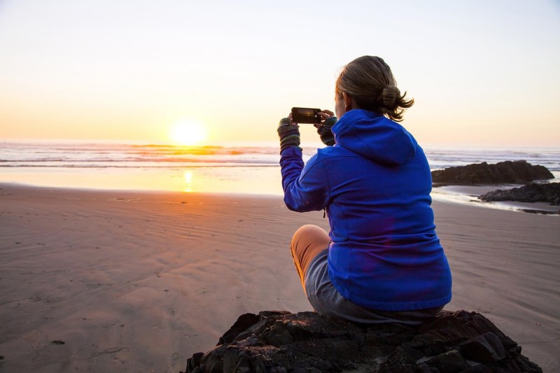 Imagen mujer sacando foto puesta de sol con móvil
