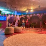 Espacio dedicado a película Encanto con personajes de la película y decorado de alfombra y puffs