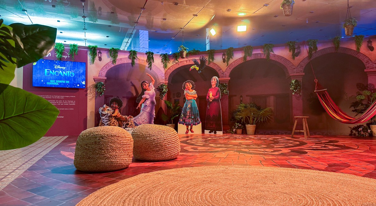 Espacio dedicado a película Encanto con personajes de la película y decorado de alfombra y puffs