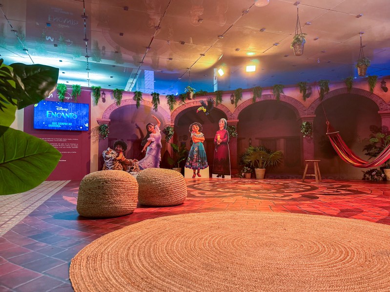 Espacio dedicado a película Encanto con personajes de la película y decorado de alfombra y puffs