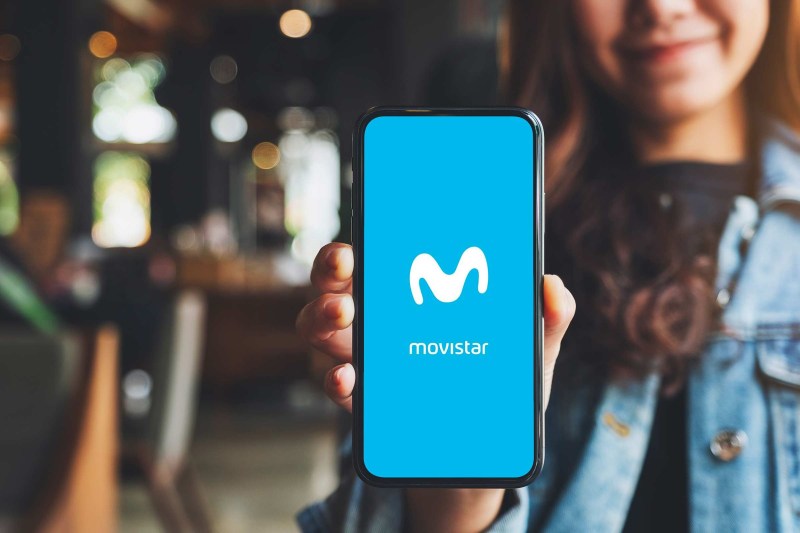 Una chica enseñando un móvil con el logo de Movistar