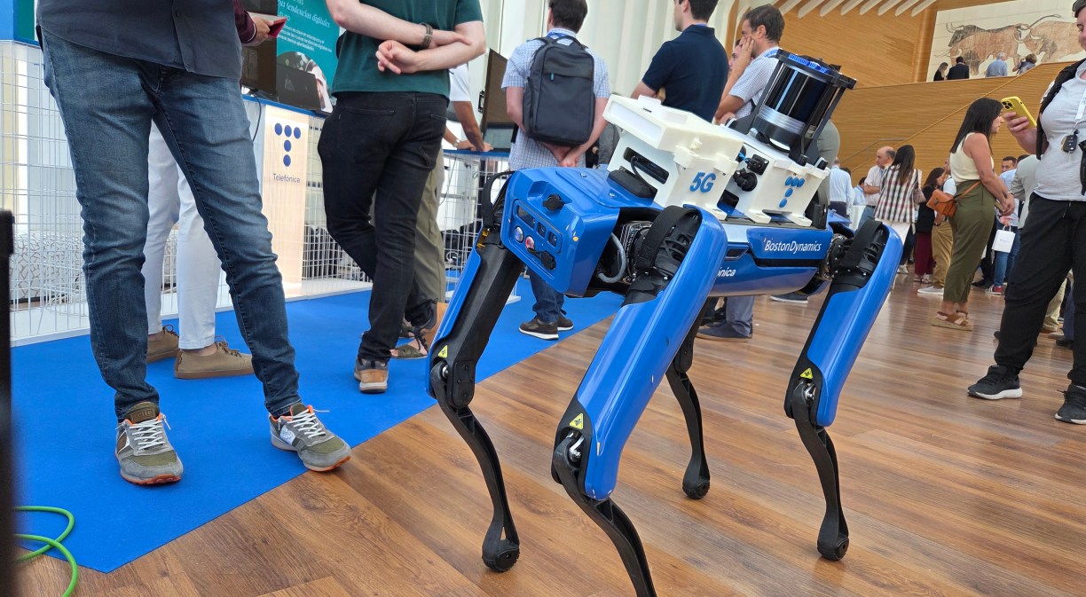Un robot similar a un perro dirigido con un mando a distancia por una persona a la que se ve medio cuerpo