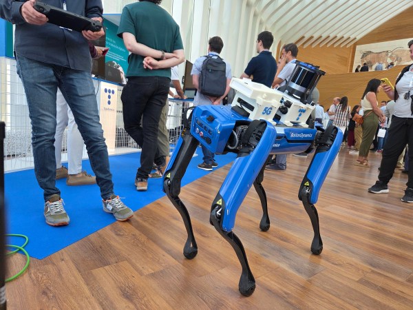 Un robot similar a un perro dirigido con un mando a distancia por una persona a la que se ve medio cuerpo
