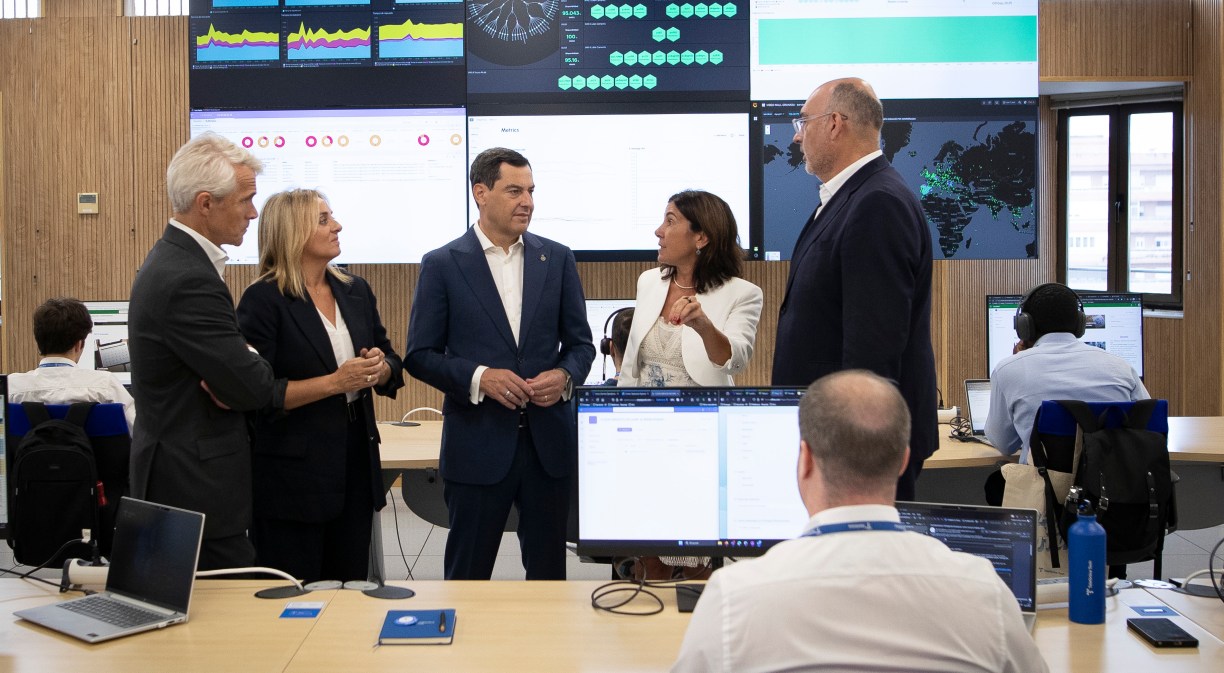 Directivos de Telefónica y representantes institucionales en el nuevo centro de Granada con un trabajador de espaldas en primer plano y pantalla al fondo.