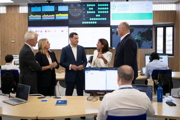 Directivos de Telefónica y representantes institucionales en el nuevo centro de Granada con un trabajador de espaldas en primer plano y pantalla al fondo.