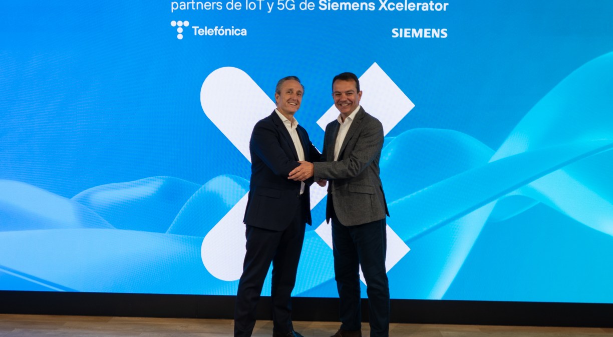 Dos hombres directivos con traje dándose la mano delante de un fondo azul