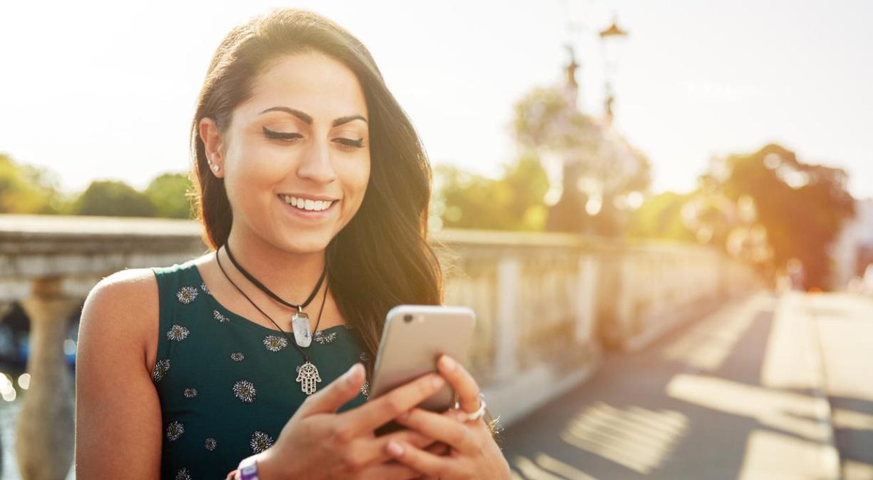 Imagen de una chica en un puente tecleando en el móvil