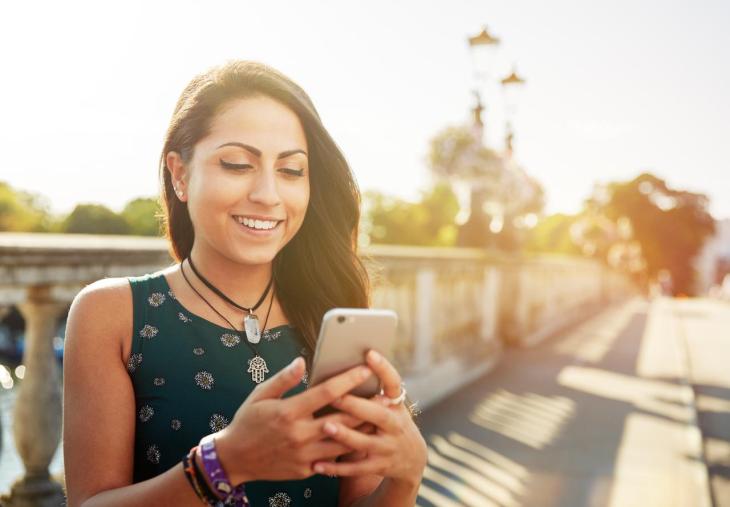 Imagen de una chica en un puente tecleando en el móvil