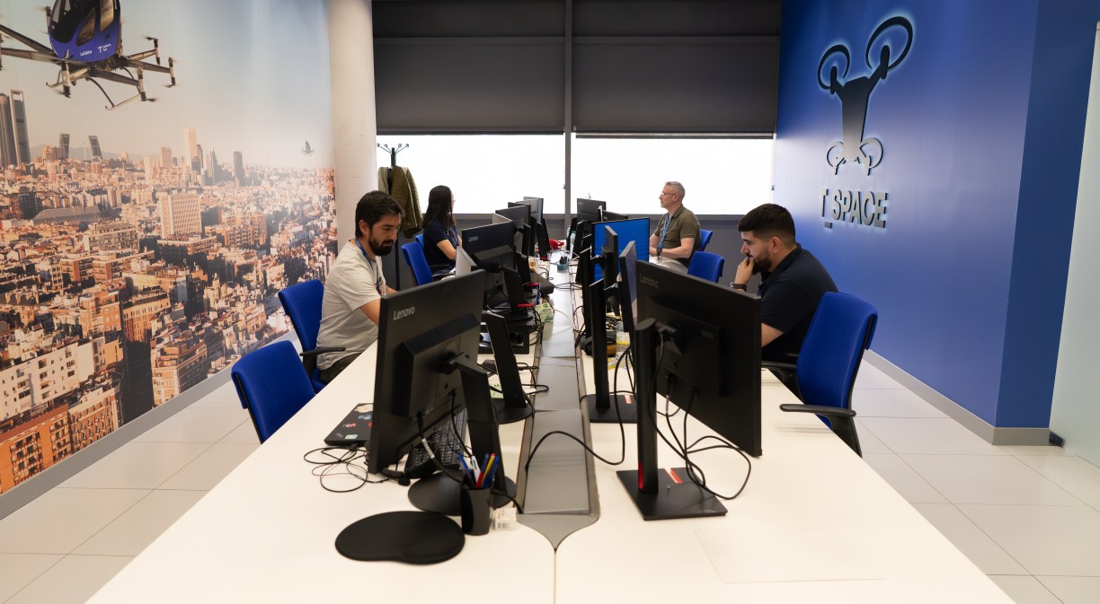 Imagen de una sala con varios pilotos alrededor de una mesa trabajando delante de un ordenador